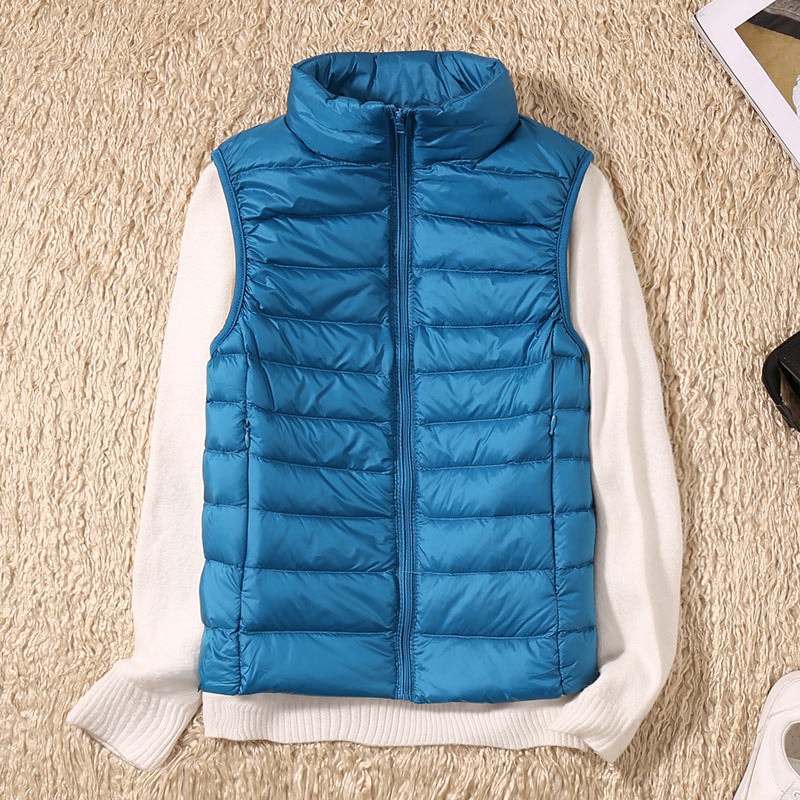 Blue quilted zip-up vest over a white sweater, viewed from above with its sleeveless shape and side pockets visible.
