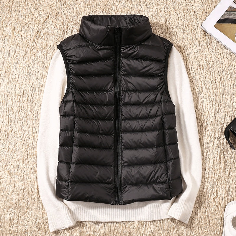 Black quilted zip-up vest arranged over a white sweater, highlighting its streamlined front and high stand collar.