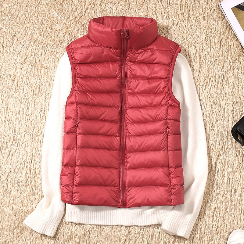 Red sleeveless quilted vest layered over a white sweater, displaying its full-length front zip and raised collar.