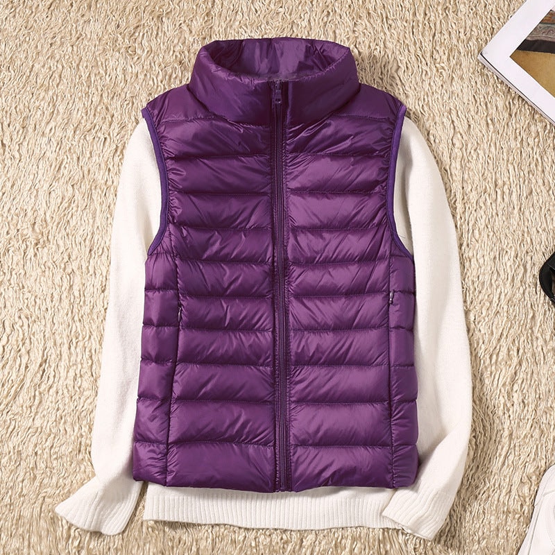 Purple quilted puffer vest over a white sweater, highlighting the sleeveless arm openings and tall stand collar.