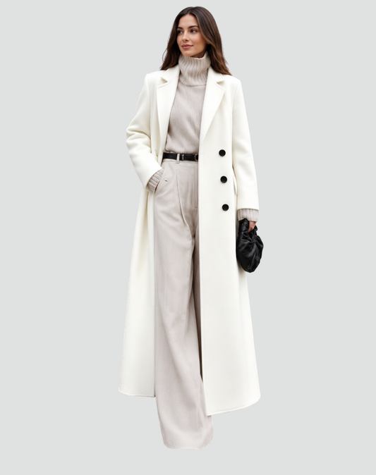 Long white double-breasted coat with wide notched lapels, worn over a light turtleneck and trousers.