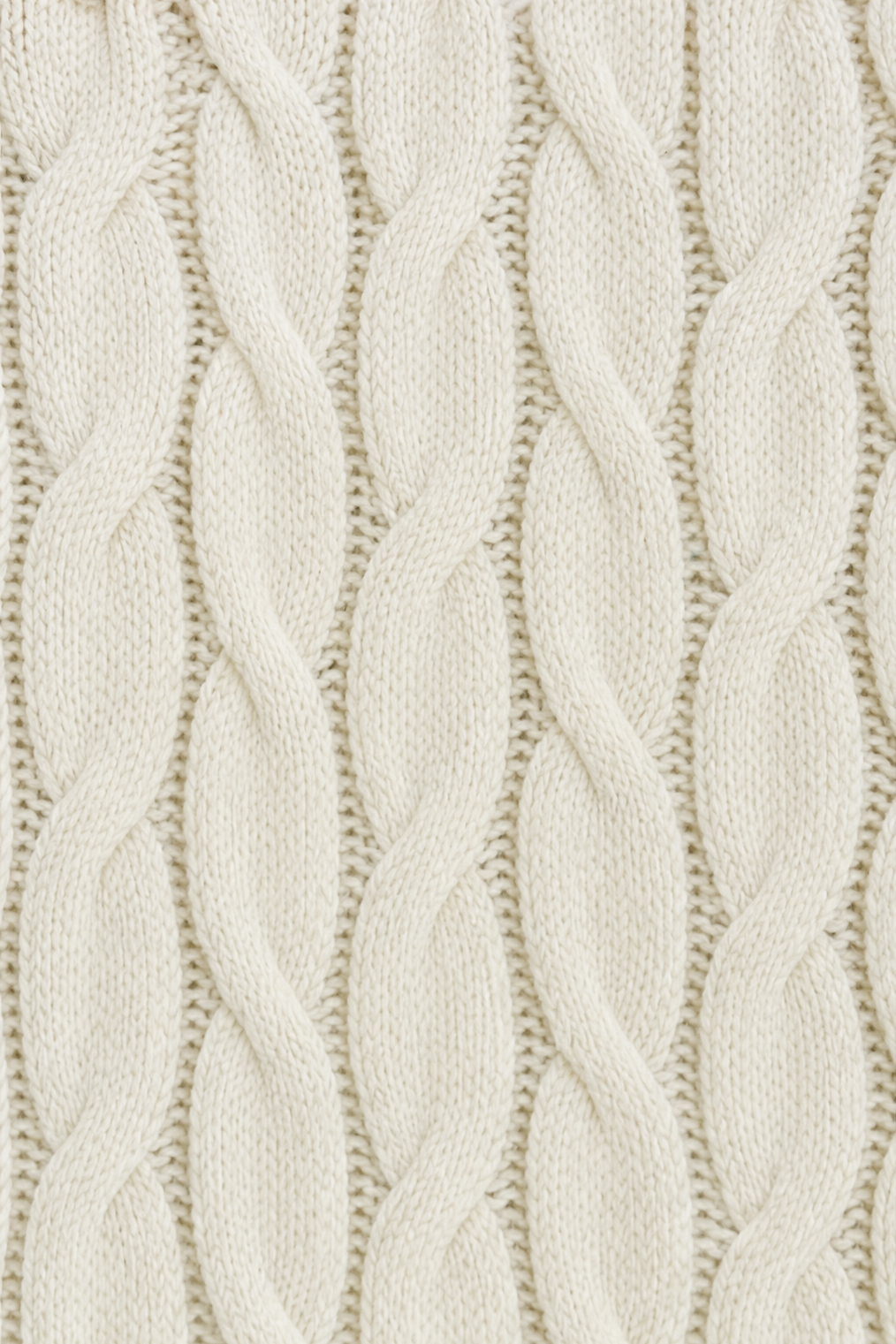 Close-up of the cardigan’s repeating vertical cable knit pattern in a light cream color.