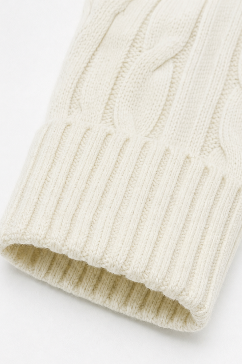 Close-up of the cardigan sleeve end showing the textured cable knit and wide ribbed cuff.