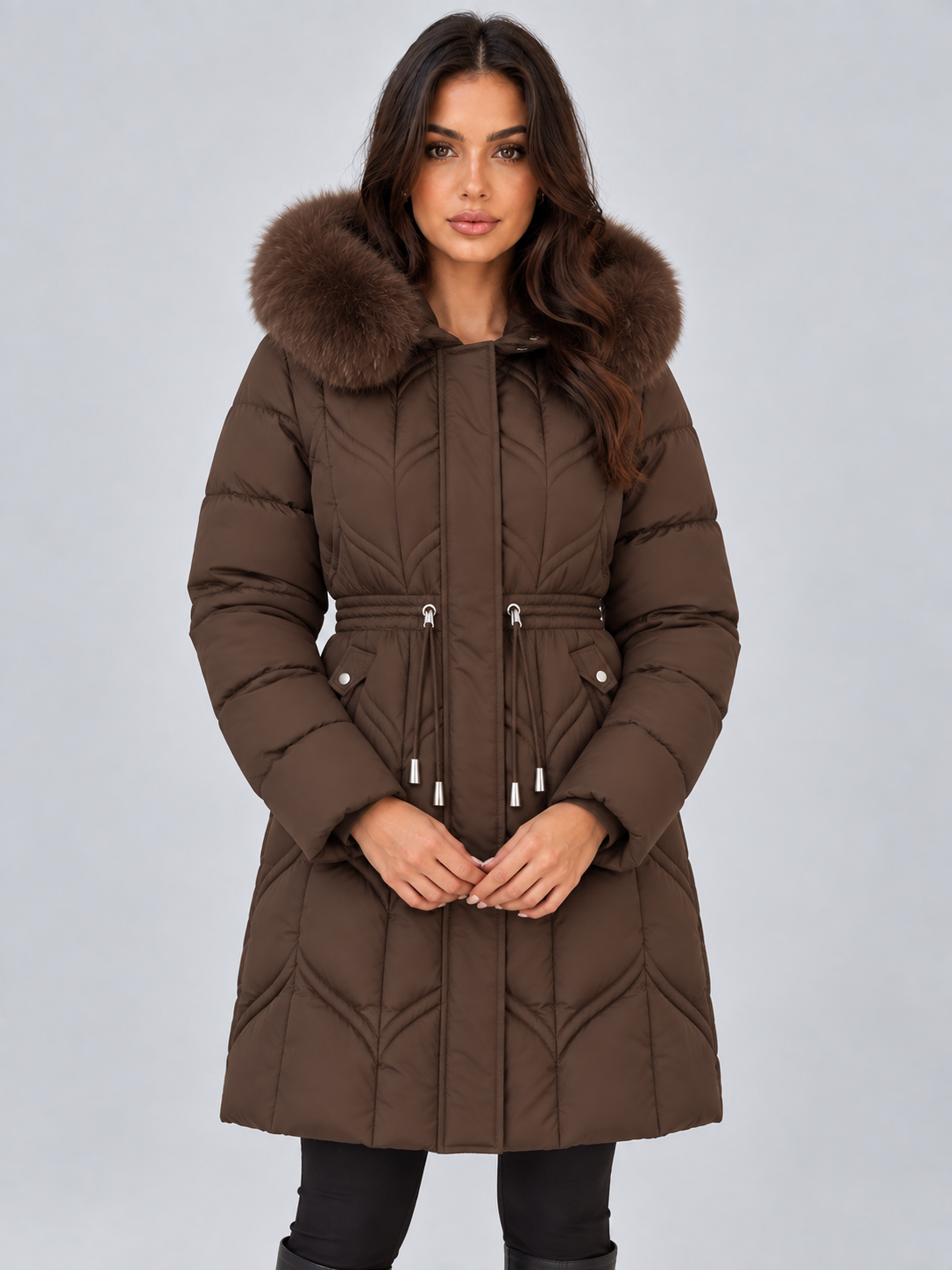 Front view of the long brown hooded puffer coat with contrasting faux fur trim, cinched waist, quilted pattern, and front pockets.