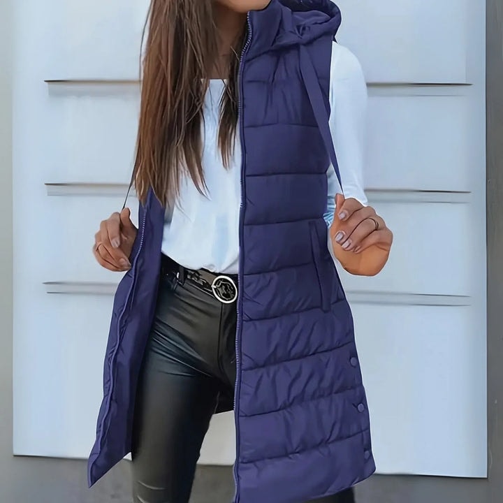Navy blue long hooded puffer vest worn open, showcasing the sleeveless layered fit, extended hem, and horizontal padded panels.