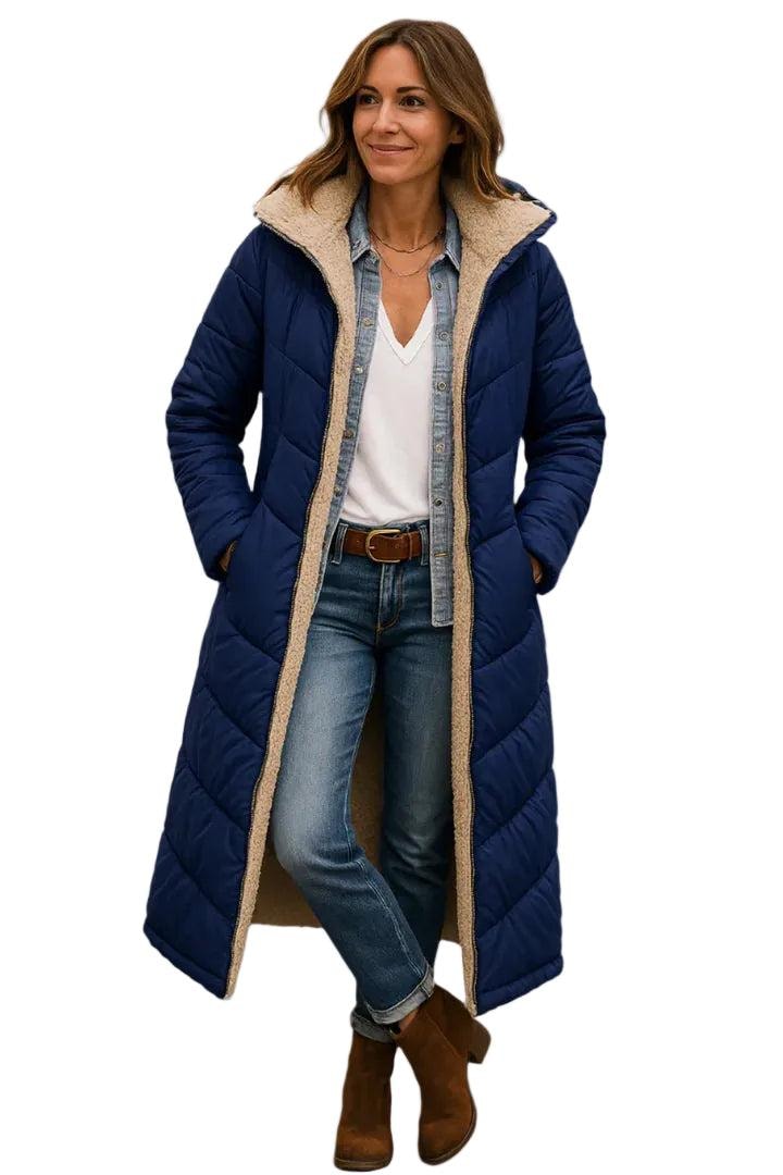 Model wearing a navy long quilted coat with hands in the side pockets and the plush-lined hood framing the face.