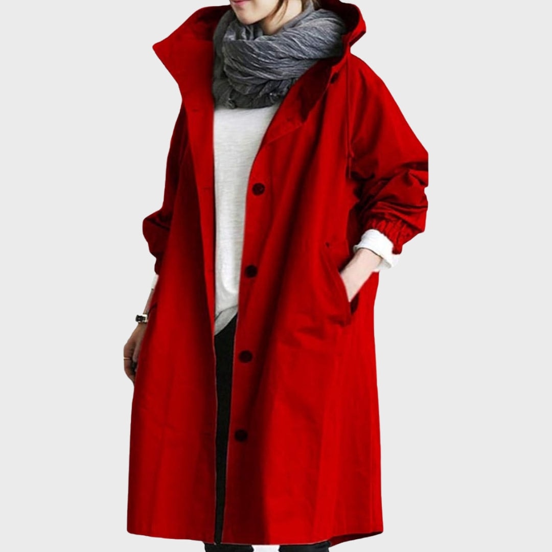 Front view of the rain coat in bright red, featuring a raised hood, dark button closure, long sleeves, and side pockets.