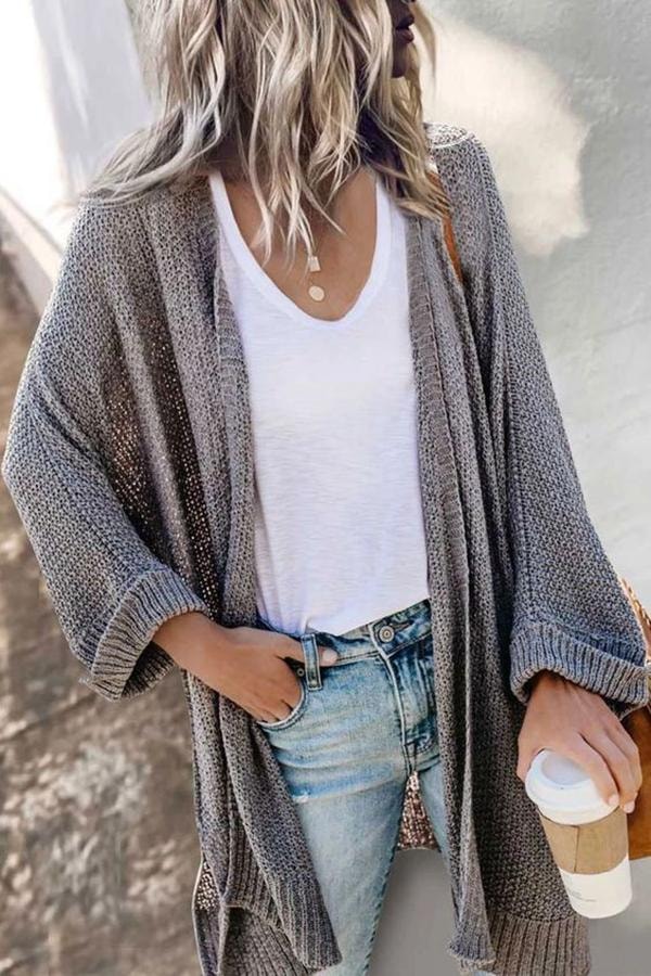 Gray long open-front cardigan with relaxed sleeves and ribbed cuffs worn over a white top and jeans.