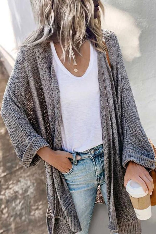 Gray long open-front cardigan with relaxed sleeves and ribbed cuffs worn over a white top and jeans.