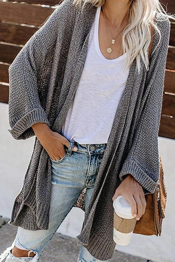 Gray cardigan styled open over a white top, showing its long front panels and relaxed cuffed sleeves.