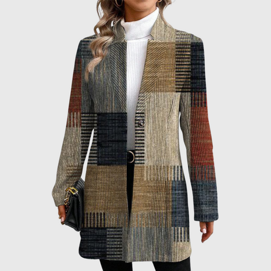Front view of a longline women's blazer with a multicolored patchwork plaid pattern, notched lapels, long sleeves, and a single-button closure over a white turtleneck.