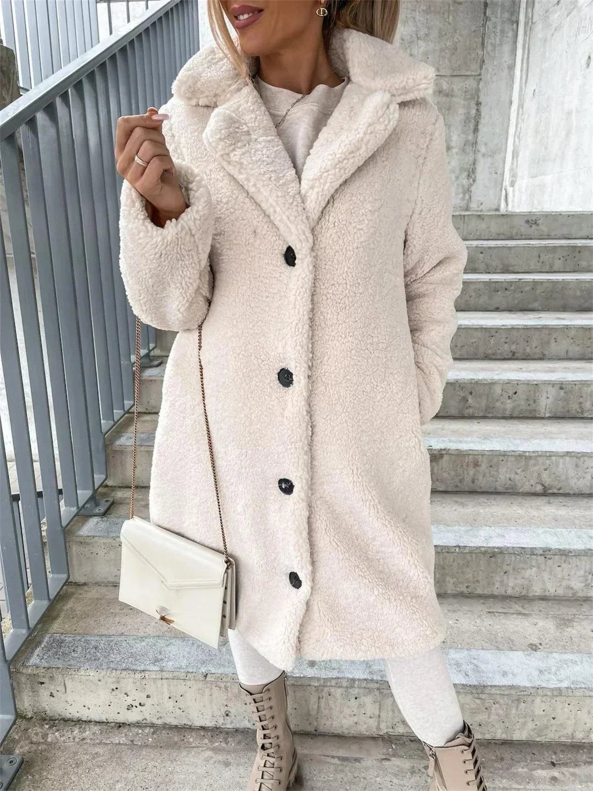 Close front view of the cream teddy coat, highlighting the wide notched collar, four-button closure, long sleeves, and side pocket openings.