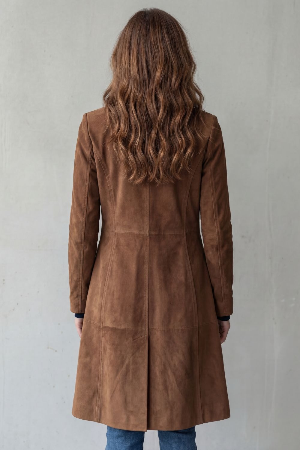Back view of the brown longline coat, highlighting the long sleeves, shaped waist, center seam, and extended hem.