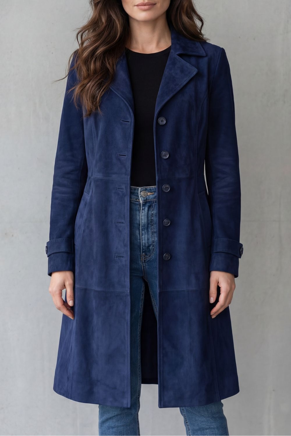 Front view of the navy longline coat worn open, featuring notched lapels, long sleeves with cuff tabs, buttons, and side pockets.