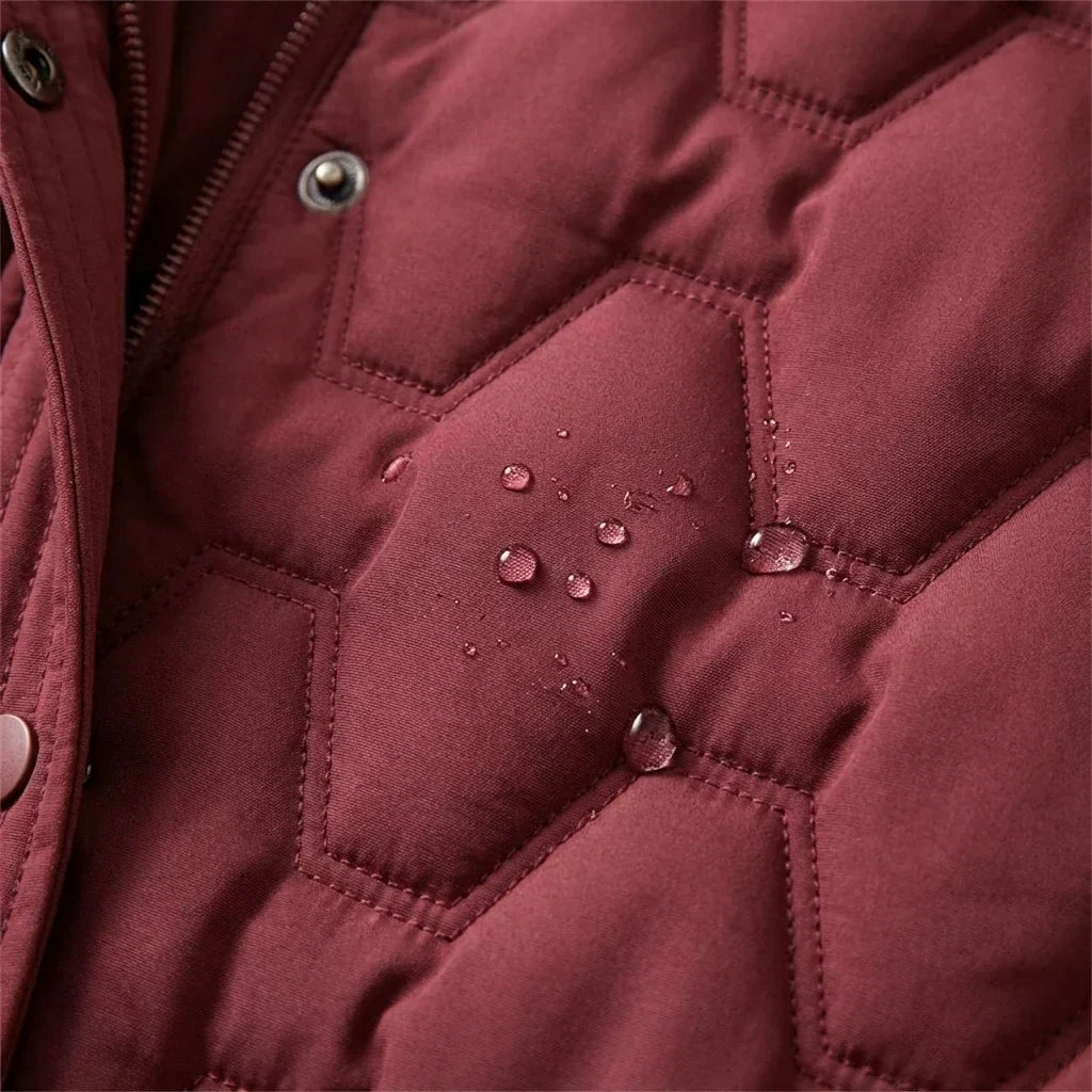 Close-up of the burgundy coat’s quilted panel, front snap, zipper edge, and visible water droplets.