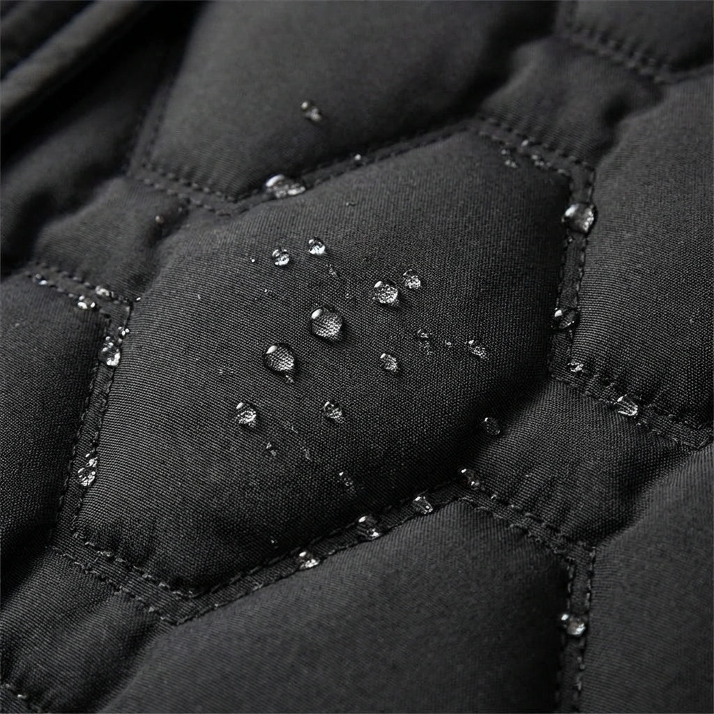 Close-up of black quilted puffer fabric with reflective water droplets along the stitched panels.