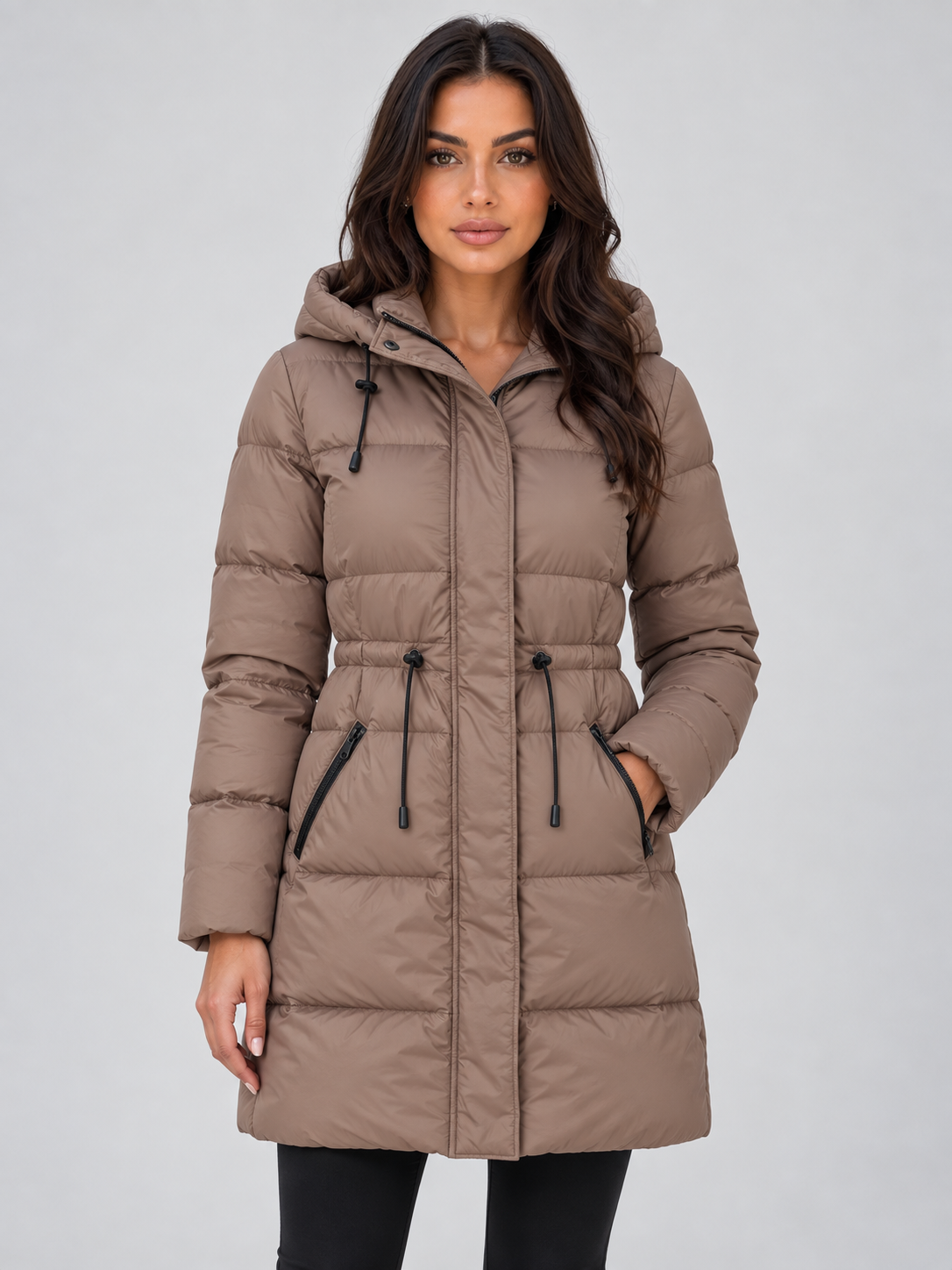 Front view of a taupe longline hooded puffer coat with a zipped front, drawstring waist, long sleeves, and zipped side pockets.