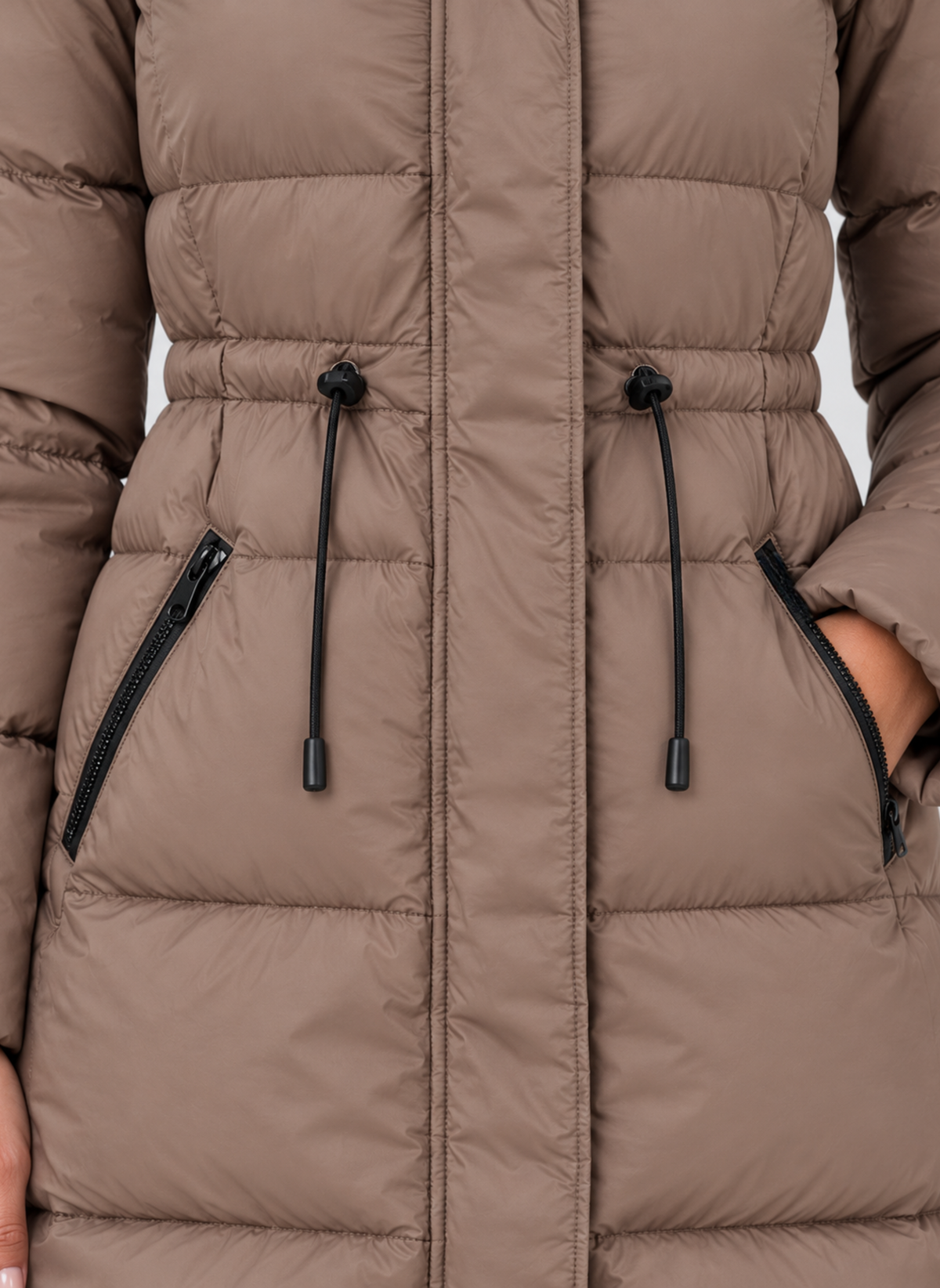 Close-up of the coat’s adjustable drawstring waist and two diagonal zipped pockets.