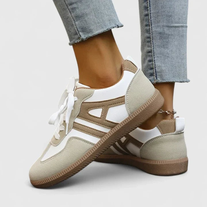 Low-top sneakers shown in a crossed side and rear view, revealing the layered contrast panels, heel pull tabs, lace-up fronts, and textured brown outsoles.