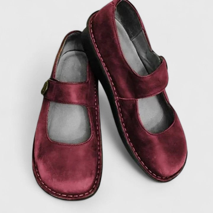 Burgundy Mary Jane flats presented at an angled view, revealing the low-profile soles, rounded fronts, and stitching detail.