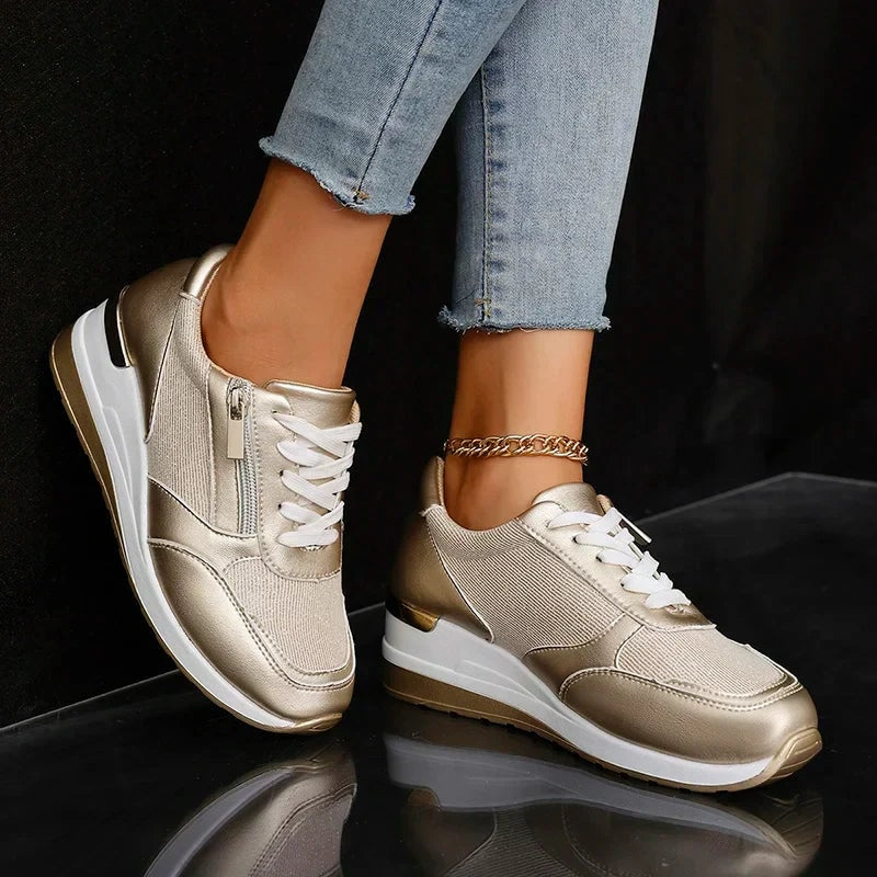 Champagne metallic platform sneakers displayed on both feet, highlighting the rounded toe, white laces, and contrasting heel detail.