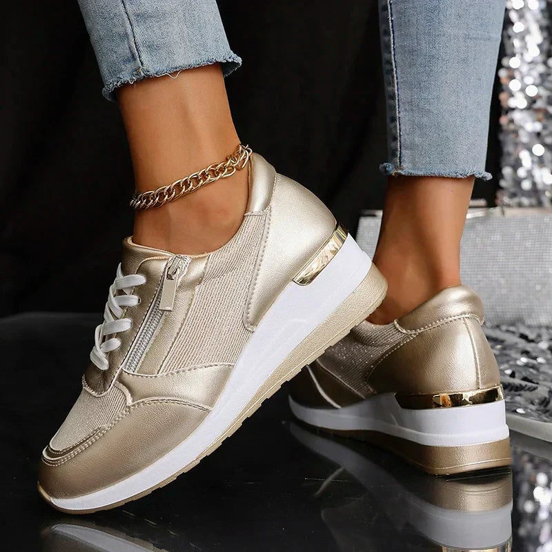 Champagne metallic sneakers shown at an angled rear-side view, emphasizing the platform height and gold-toned heel accents.