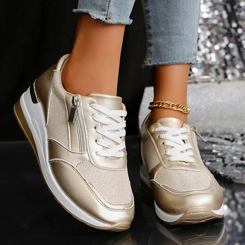 Front view of champagne metallic platform sneakers highlighting the paired lace-up vamps and rounded toe caps.