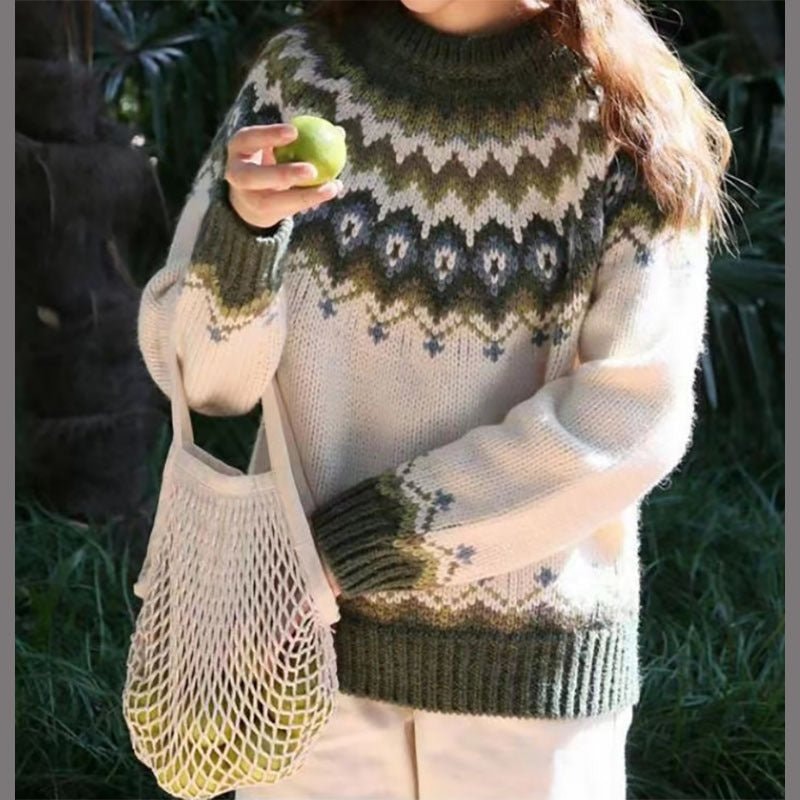 Light sweater with an olive green, gray, and dark blue Nordic-inspired yoke, contrasting ribbed cuffs and hem, paired with light trousers.