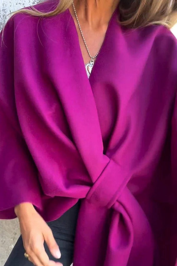 Bright magenta cape jacket with overlapping front panels gathered at the waist and wide sleeves.