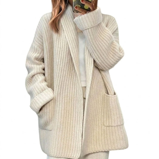 Light cream open-front ribbed cardigan with long sleeves, wide turn-back cuffs, and two front patch pockets, shown over a light top.
