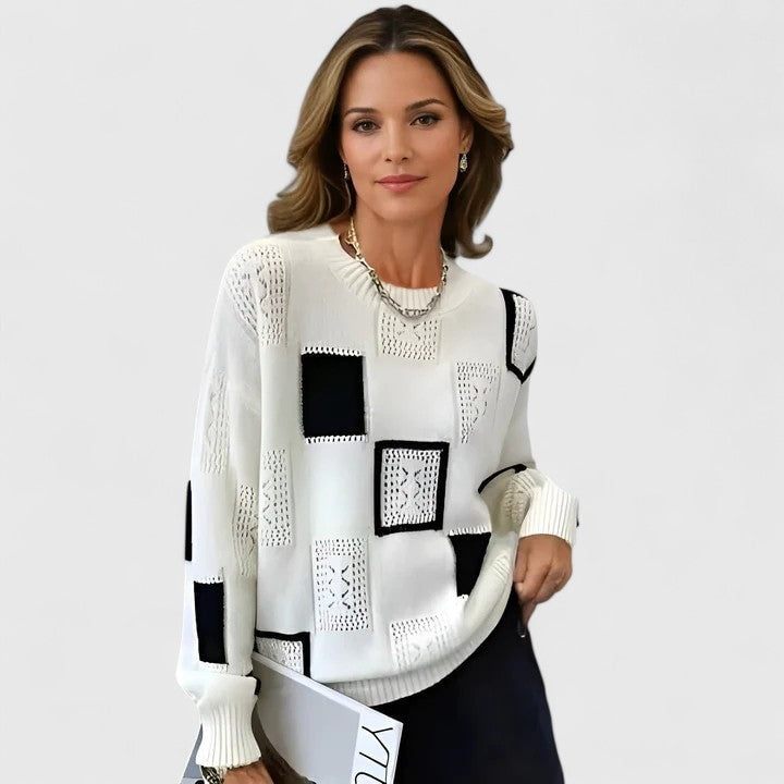 White crew neck sweater with contrasting black patchwork panels, openwork square accents, long sleeves, and ribbed cuffs.