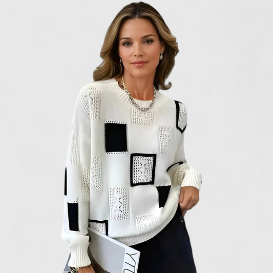 White crew neck sweater with contrasting black patchwork panels, openwork square accents, long sleeves, and ribbed cuffs.