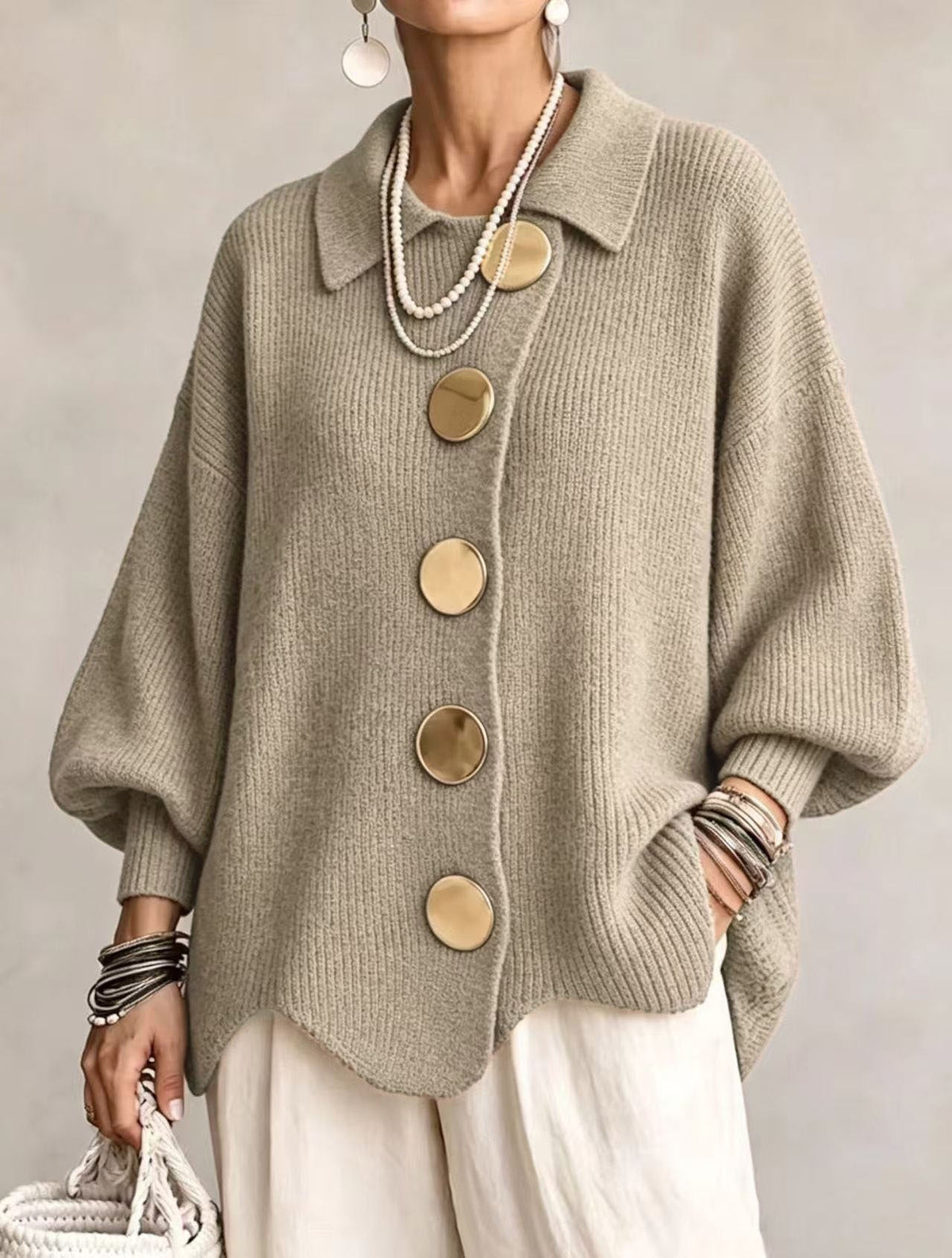 Taupe oversized cardigan with a pointed collar, five large round buttons, voluminous sleeves, and a relaxed curved hem.
