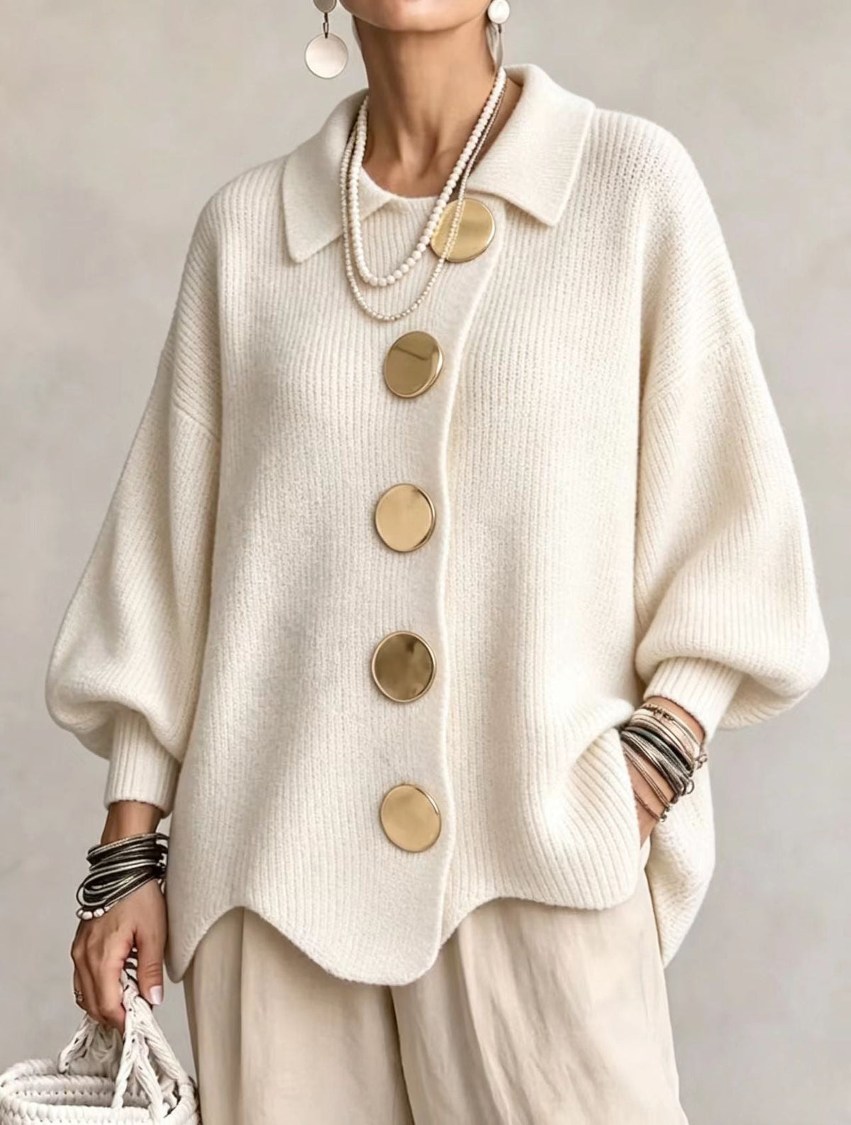 Cream oversized button-front cardigan with a pointed collar, five large round buttons, balloon sleeves, and ribbed cuffs.
