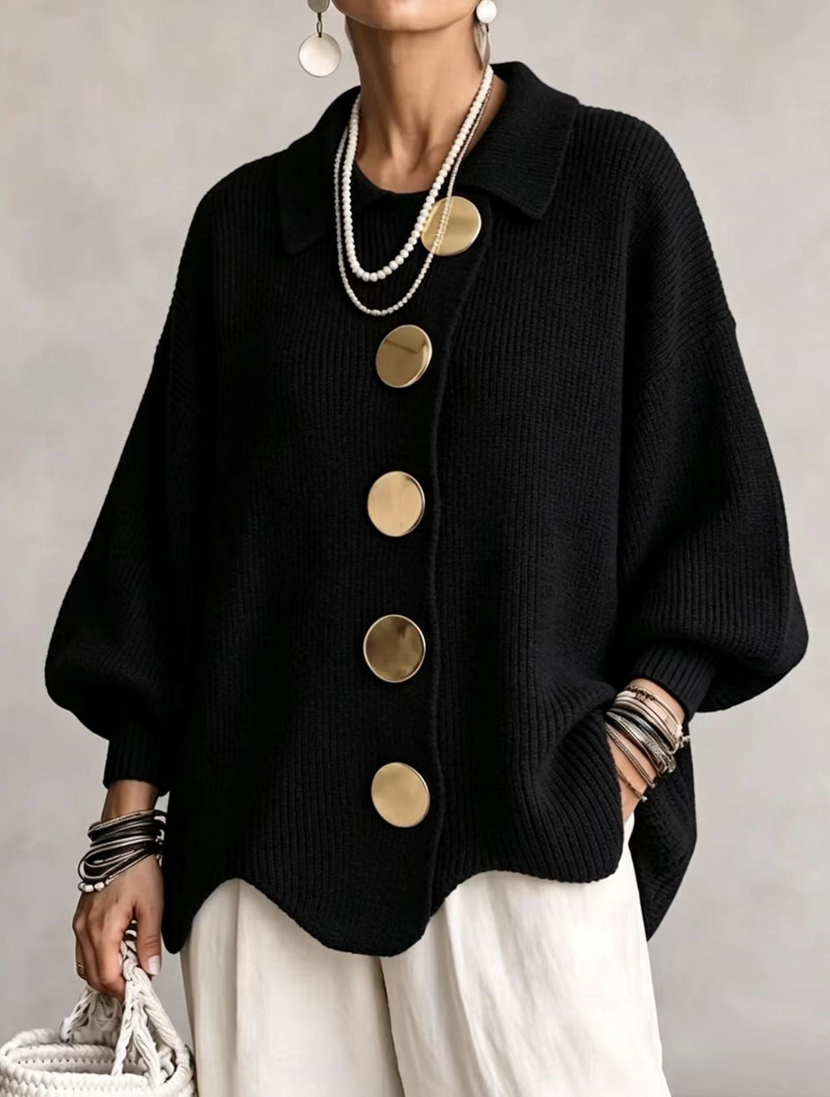 Black oversized cardigan featuring a pointed collar, five large round front buttons, balloon sleeves, and ribbed cuffs.