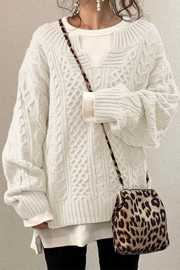 White oversized cable knit V-neck sweater styled over a longer white top, showing its textured front and roomy sleeves.