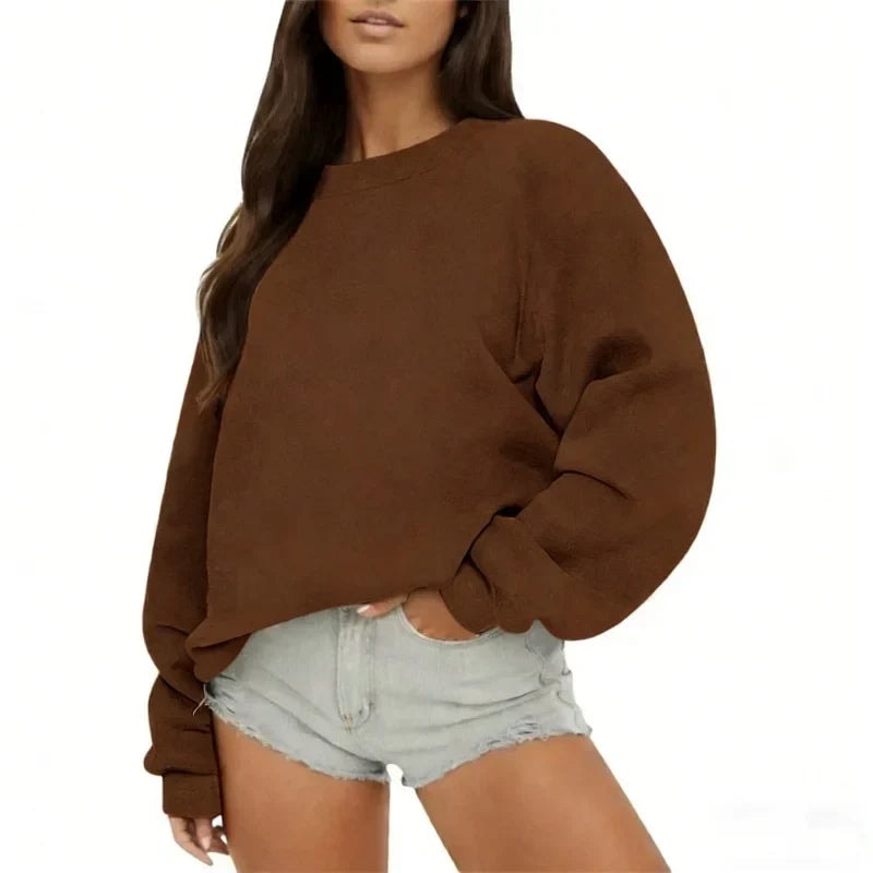 Brown oversized crew neck sweatshirt worn casually with light denim shorts and long relaxed sleeves.