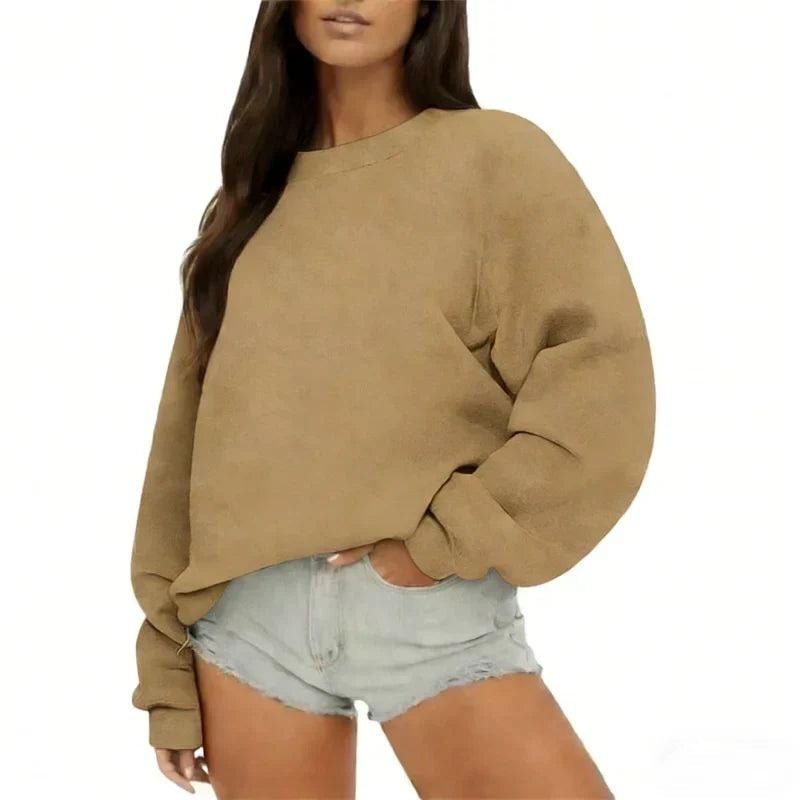 Tan oversized sweatshirt on a model, showing its loose silhouette, classic neckline, and ribbed sleeve cuffs.