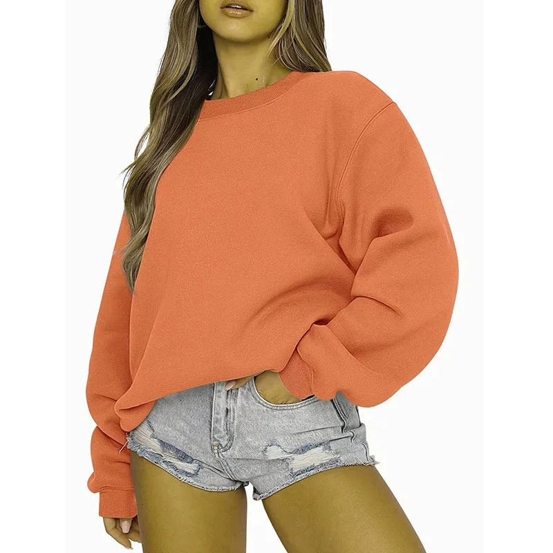 Orange oversized crew neck sweatshirt styled with denim shorts, featuring dropped shoulders and a softly gathered hem.