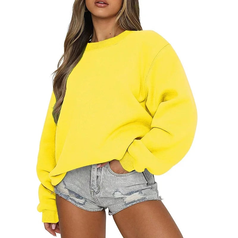 Bright yellow oversized crew neck sweatshirt worn casually with denim shorts, featuring dropped shoulders and ribbed cuffs.