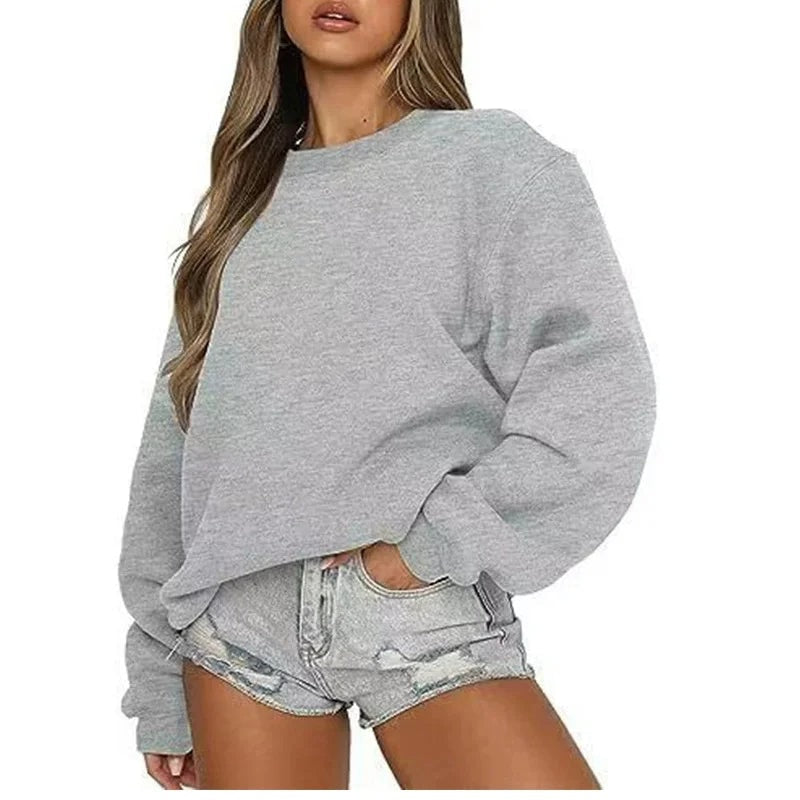 Light gray oversized sweatshirt worn with distressed denim shorts, showing the simple crew neck and loose sleeves.