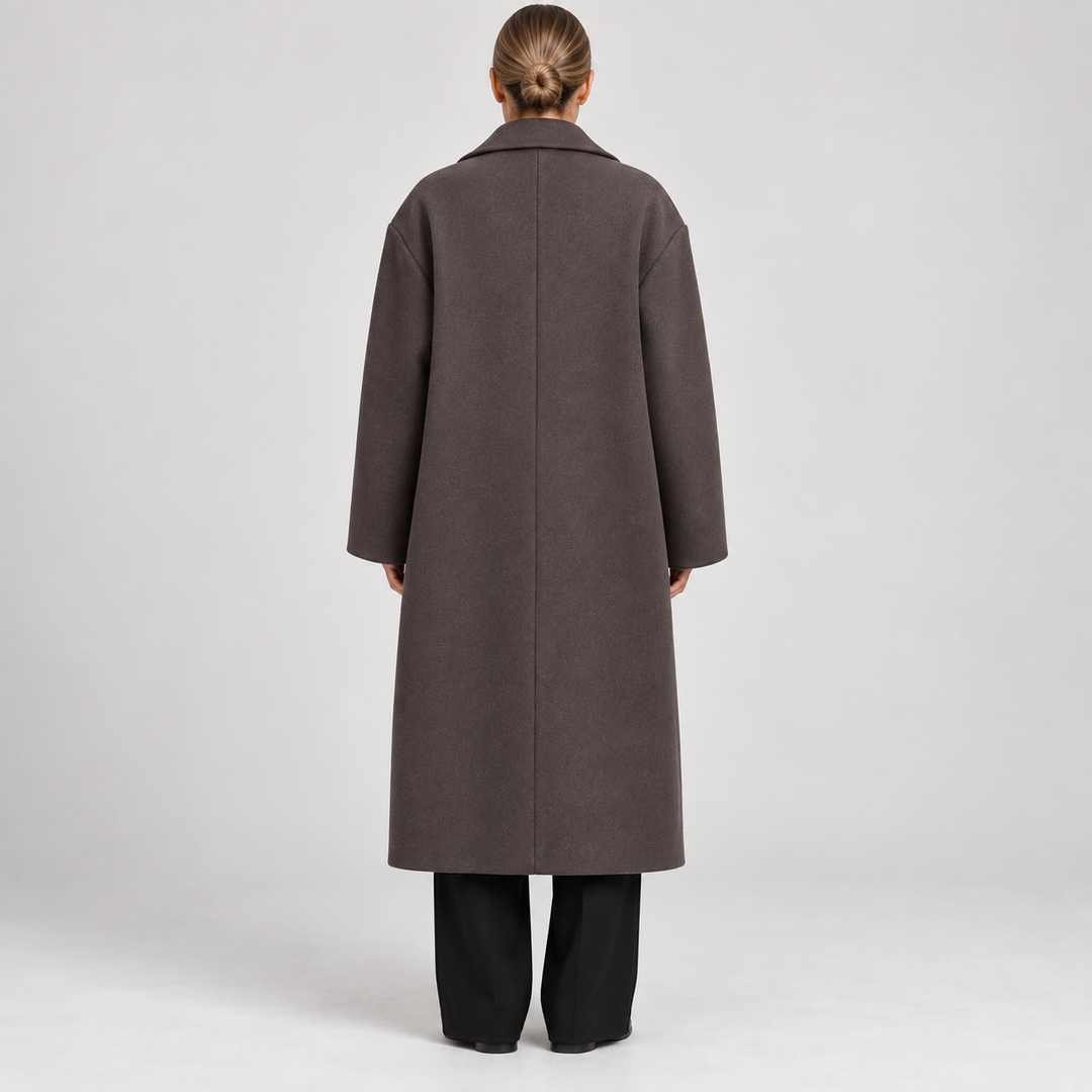 Straight-on back view highlighting the coat’s long clean lines, relaxed sleeves, and below-the-knee hem.