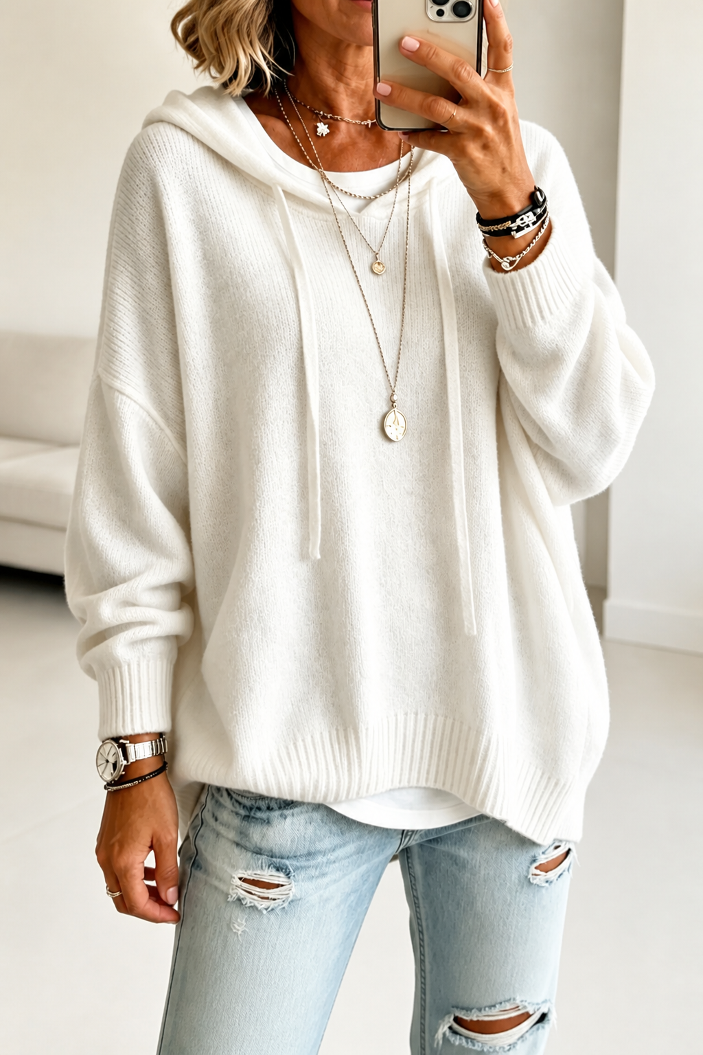Mirror view of the ivory oversized hooded sweater, showing its relaxed body, long sleeves, and ribbed lower edge.
