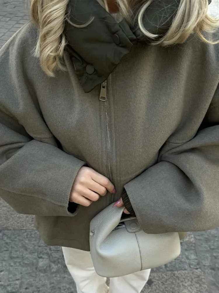 Close overhead view highlighting the jacket's front zip closure, quilted collar, and oversized sleeves.