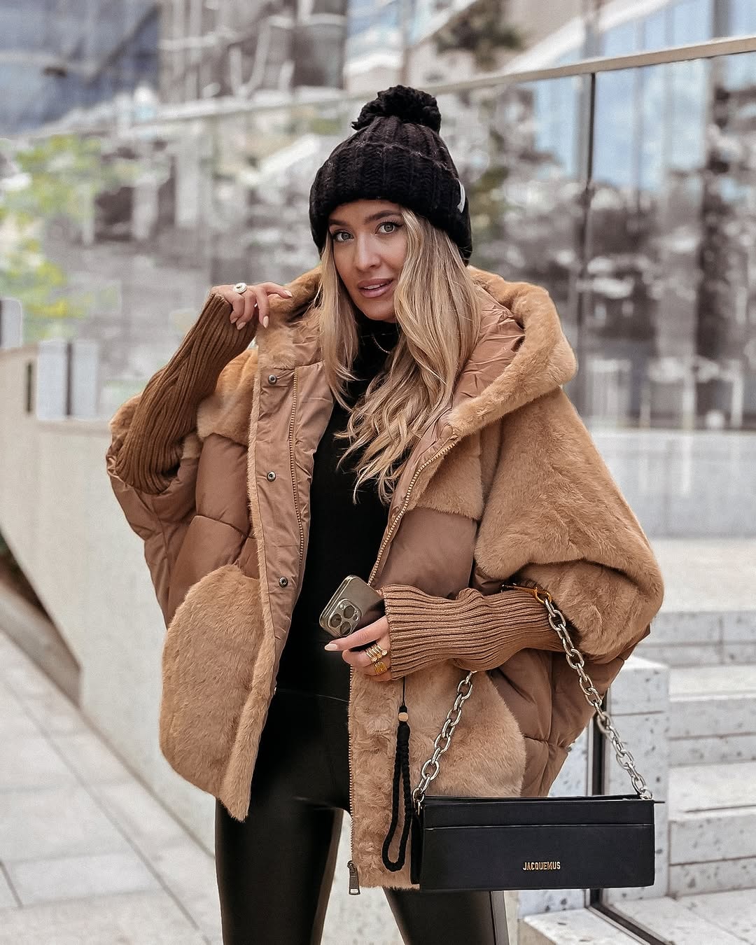 Camel oversized hooded puffer jacket with plush panels, ribbed cuffs, and front closures styled for a city outfit.