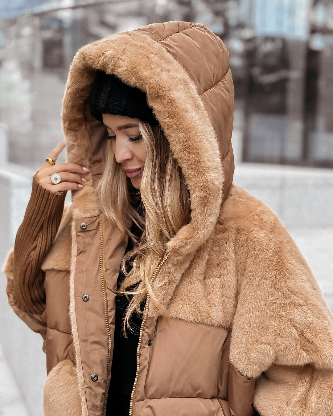 Close view of the camel puffer jacket’s generous hood, plush edging and shoulder panels, with its front snap closures visible.