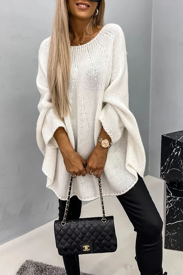 White oversized knit poncho sweater featuring a relaxed silhouette, wide long sleeves, open knit texture, and tunic-length curved hem.