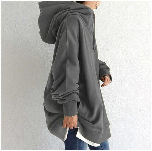 Side view of the charcoal longline zip-up hoodie showing its roomy silhouette, extended hem, hood, and gathered sleeve cuff.