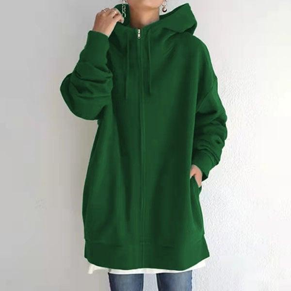 Front view of the oversized longline zip-up hoodie in deep green, worn over a white top with one hand in a side pocket.
