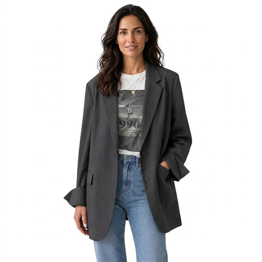 Front view of a charcoal oversized two-button blazer styled open over a graphic T-shirt and jeans, with notched lapels, flap pockets, and split cuffs.